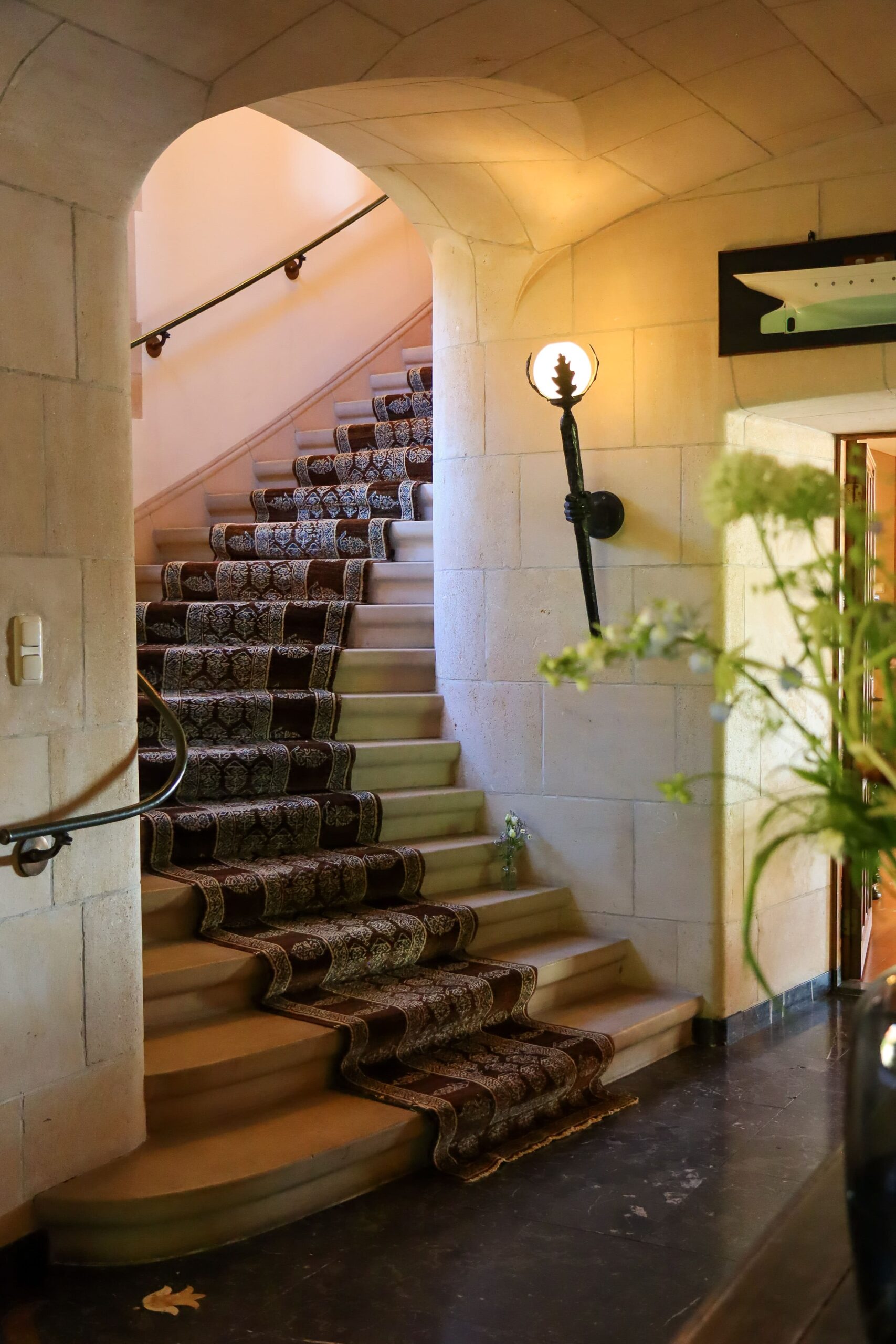 De hal met een mooie stenen trap en daarop gedrapeerd een fraai tapijt