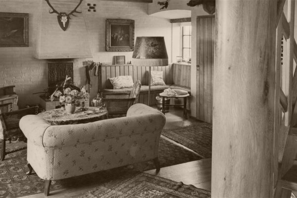 Een zwart-wit foto uit het verleden waarop een zitkamer te zien is