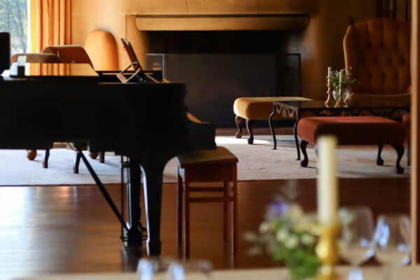 Een foto van de eetkamer van Landhuis Noorderheide met uitzicht op de haard en de piano in de zitkamer