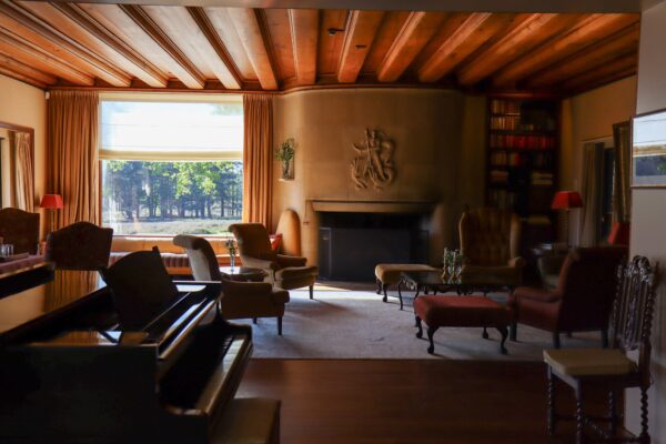 De zitkamer van Landhuis Noorderheide met een piano en een stenen haard